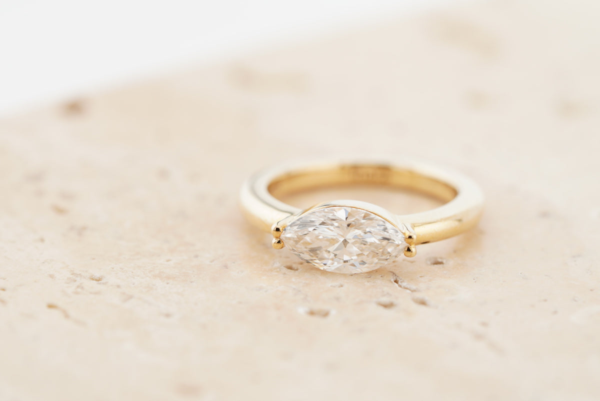 Leila Ring in 10K yellow gold with a marquise-cut lab-grown diamond, on travertine